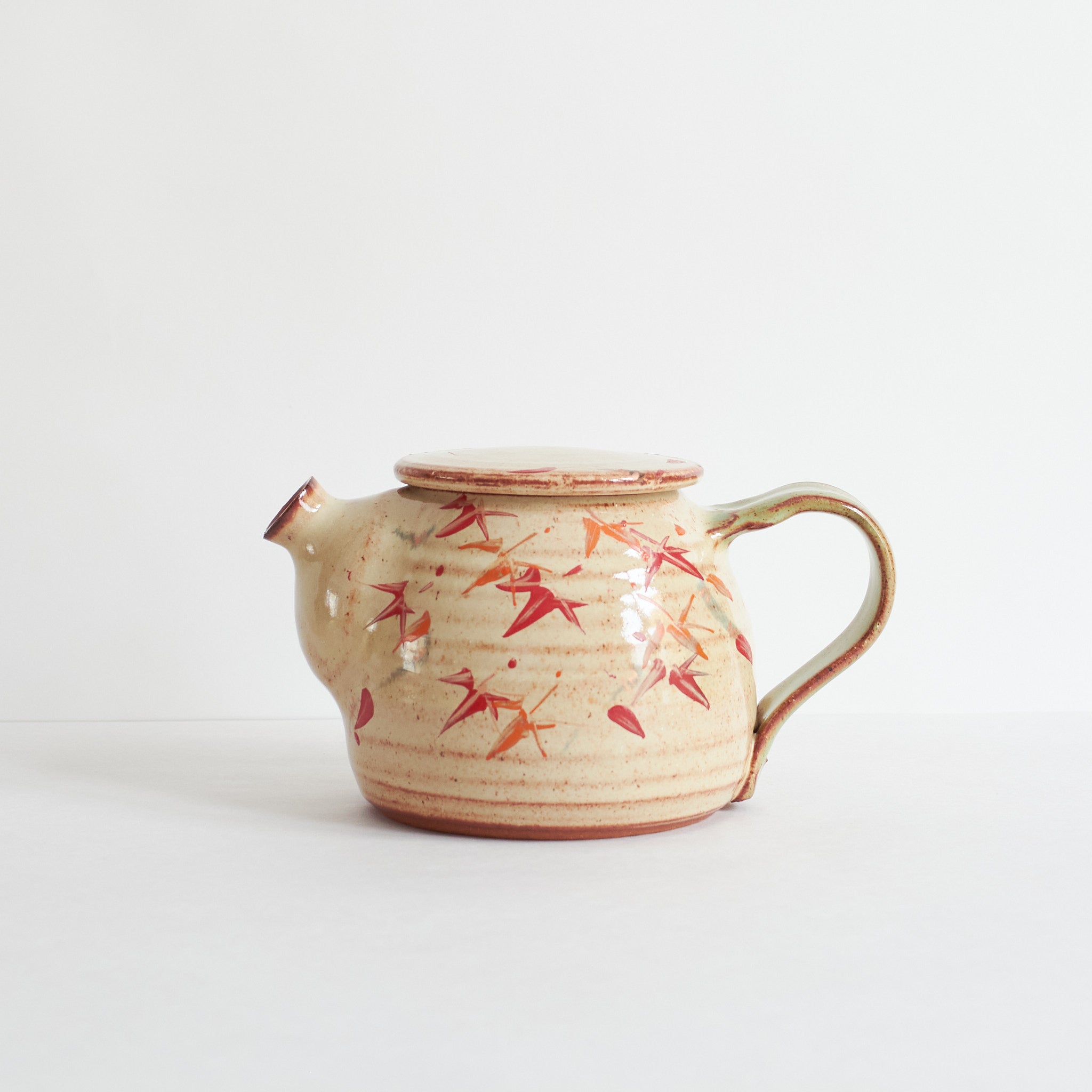 Ceramic teapot with japanese maple designs on a white background