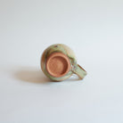 Bottom of ceramic mug on a light gray background.